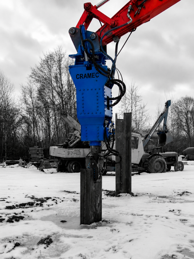 CRAMEC UP/DOWN hydraulic pile driving hammer mounted on an excavator for steel pile installation.